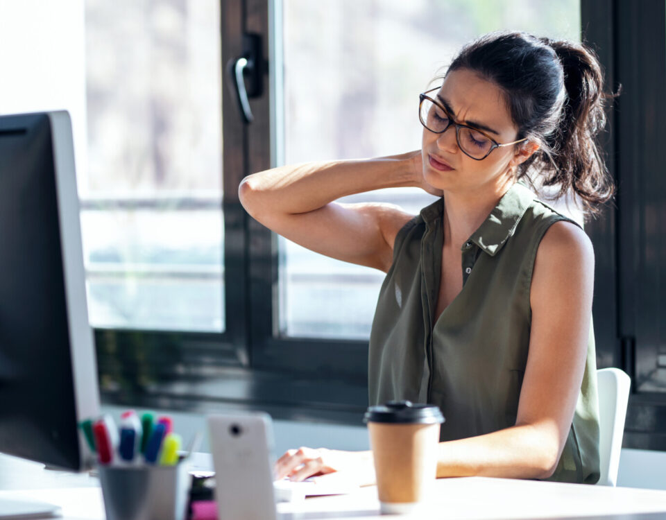 person experiencing neck pain at their office desk in vancouver bc