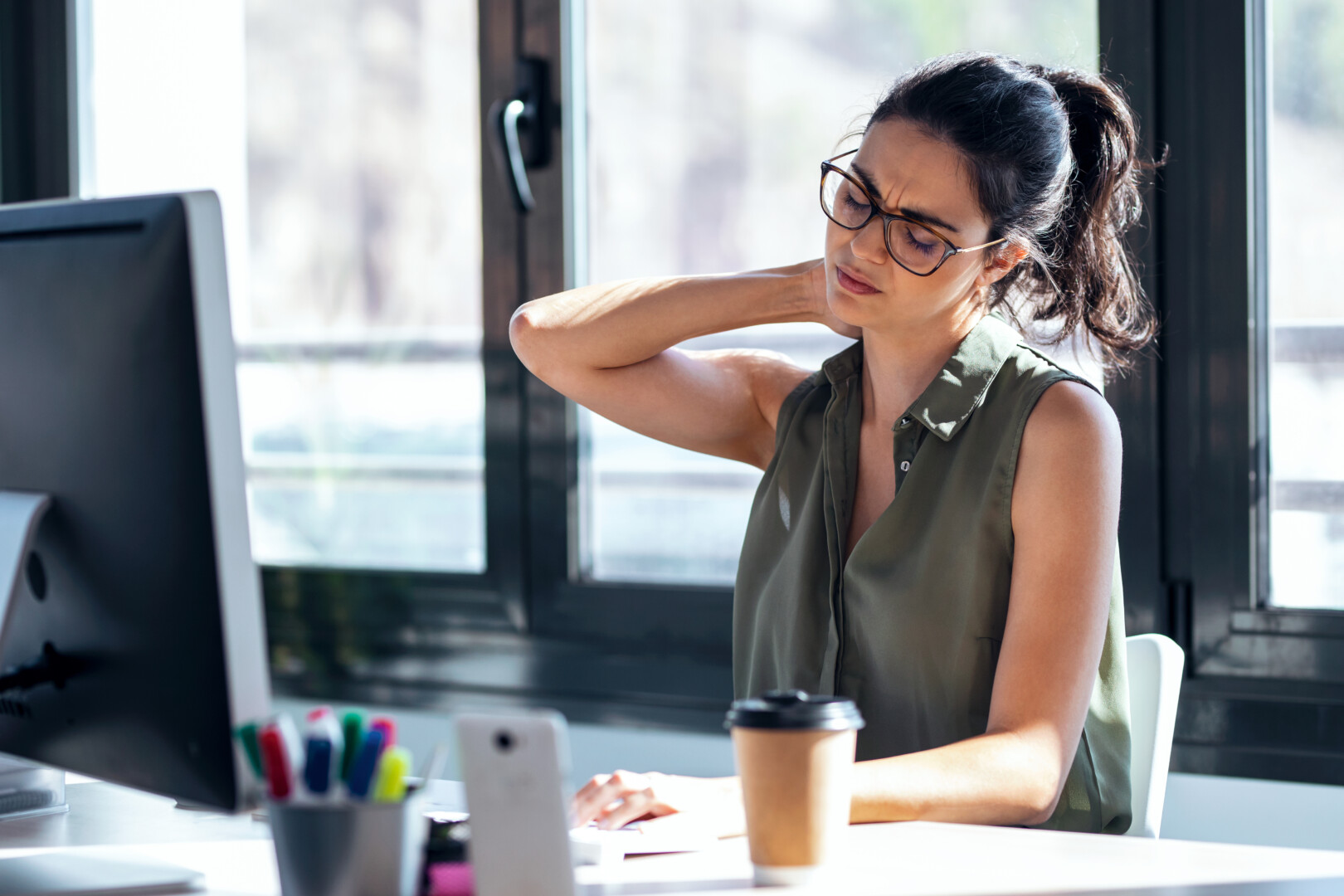 person experiencing neck pain at their office desk in vancouver bc